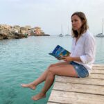 Jeune femme lisant un guide sur un pont en Méditerranée